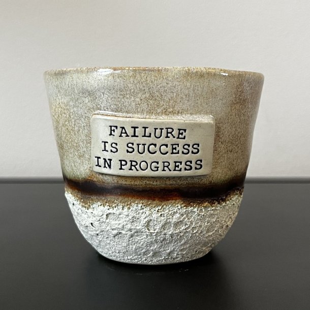 Krus med teksten "Failure is success in progress" 